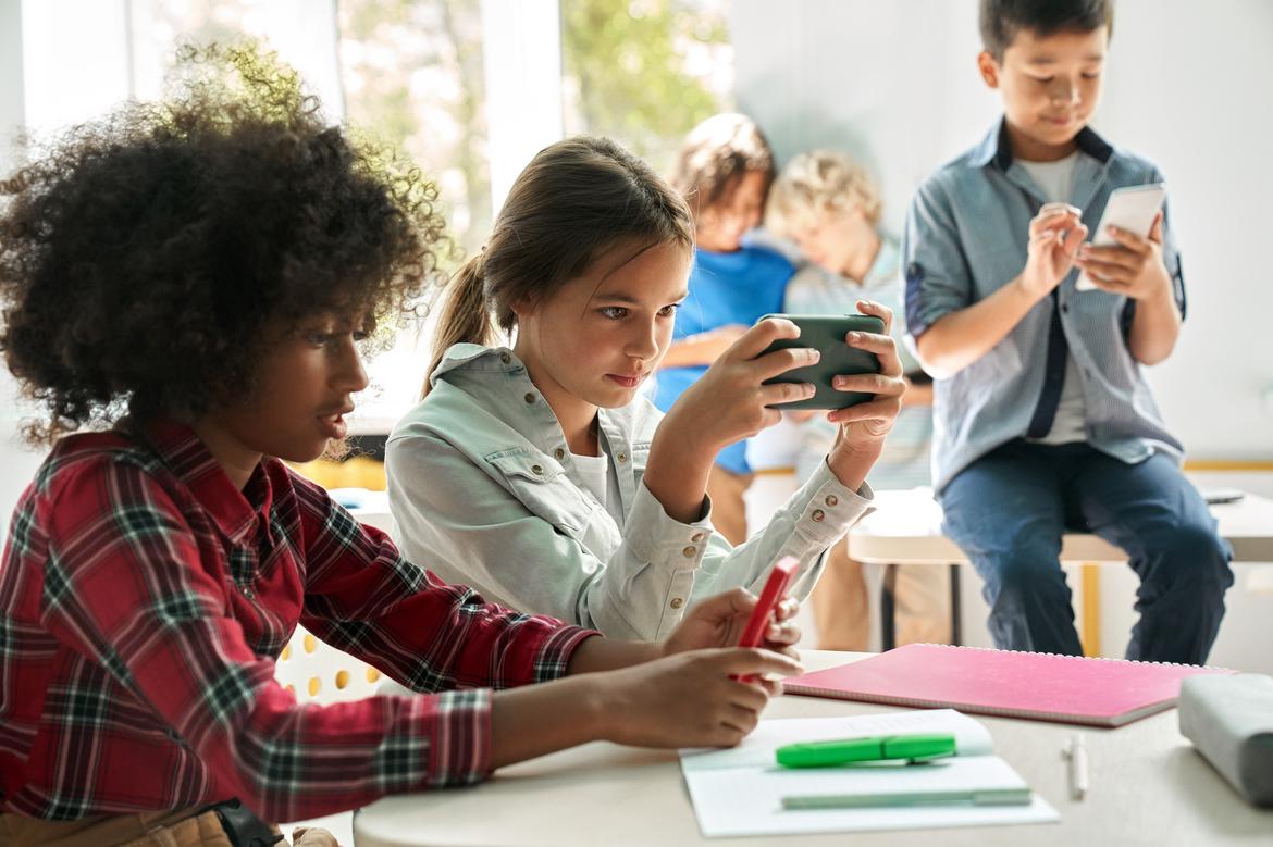 Kinder mit Smartphones in einem Klassenzimmer